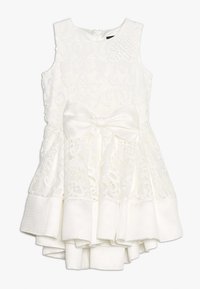 Witte mouwloze jurk met een ingewikkeld kantpatroon, een getextureerde strik rond de taille en een gelaagde, gerimpelde rok met contrasterende stoffen accentueringen.