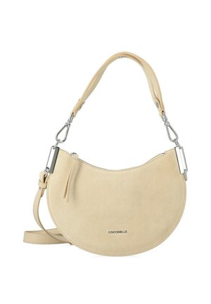 Beige halfmaanhanger suède handtas met afneembare band, zilverkleurige hardware, ritssluiting en "Coccinelle" logo aan de voorkant.