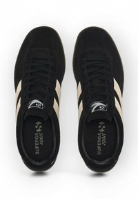 Coppia di scarpe sportive nere in suede con strisce beige, lacci neri e solette brandizzate con la scritta "Superga Sport", viste dall'alto.
