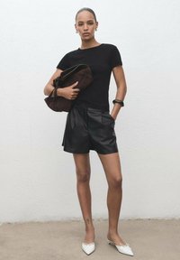 Black fitted t-shirt, high-waisted black leather shorts, white pointed flats, large brown handbag, minimalistic design, smooth texture.
