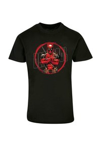 Svart bomulls t-skjorte med grafikk av en rød og svart figur med en sirkulær logo i bakgrunnen, armer korslagte, og sverd.