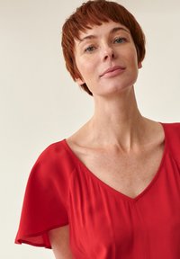 Rød bluse med V-hals og korte, flyvende ærmer. Letvægtsstof med bløde draperinger. Glat tekstur og enkle design detaljer.
