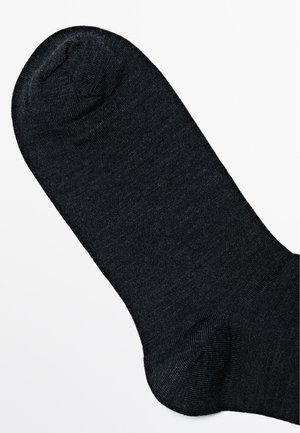 Calza nera con un tessuto liscio e testurizzato. Presenta una punta arrotondata e un tallone rinforzato. Design semplice, senza motivi o accenti.