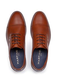 Chaussures habillées en cuir marron avec une finition lisse, dotées d'un avant lacé, d'un bout arrondi, de détails de couture subtils et d'une étiquette de semelle intérieure sombre.