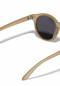 Occhiali da sole tondi con montatura traslucida color tan e lenti polarizzate scure. Presentano una stanghetta sottile e curva per un comfort ottimale durante l'indossamento.