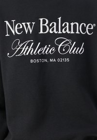 Sort sweatshirt med hvid broderet tekst: "New Balance Athletic Club, BOSTON, MA 02135." Teksten benytter en blanding af serif- og kursiv skrifttyper.