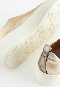Sneakers con una toma metallic oro e argento, finitura testurizzata e una suola in gomma bianca con un motivo a battistrada geometrico.