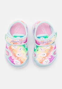 Sandały dziecięce w tęczowych kolorach z pastelowo-niebieskimi akcentami. Charakteryzują się zapięciem na rzep, wzorami chmur oraz świecącymi detalami w podeszwie.