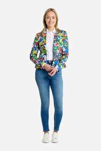 Colorful blazer featuring cartoon prints, tailored design, and vibrant patterns, paired with fitted jeans and white sneakers.