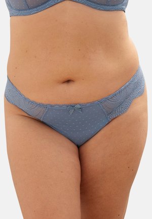 Woman wearing blue lace and mesh underwear with a small bow on the front, showing midsection and upper thighs against a neutral background.