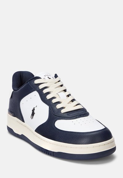 Valged ja mereväe sinised tennisetossud tekstureeritud nahast ülaservaga, kreemjad paelad, perforatsioonid varvaste juures ja logo külgedel. Ümardatud kummist tald.