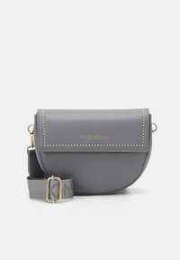 Šedá kožená crossbody taška s kulatým tvarem, zlatými hroty a logem. Obsahuje odnímatelný popruh s vyznačenou sponou.