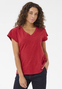 Červené tričko s výstřihem do V a krátkými rukávy s ohrnutím; vyrobené z texturované, lehké tkaniny; má volnější střih a zakřivený lem.