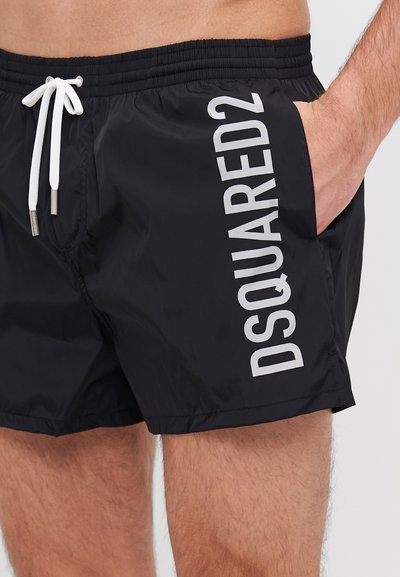 Shorts de bain noirs en tissu léger avec une taille élastique à cordon de serrage, featuring un grand texte blanc "DSQUARED2" sur le côté.