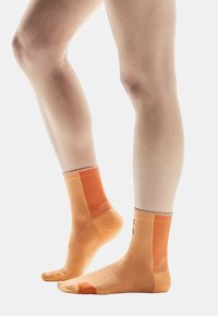 Oranje sportsokken met een textuurdesign, geribde bovenkant, een versterkte teen en enkel lengte. Zacht stof met ademende delen.
