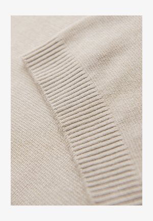 Beige gebreide stof met een gladde textuur, met een ribbelgedeelte langs één rand, wat het subtiele patroon en het zachte materiaal benadrukt.