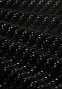 Schwarzer Strickstoff mit einem strukturierten, offenen Gewebe-Muster, das diagonale Linien und kleine, weiße Akzentquadrate aufweist.