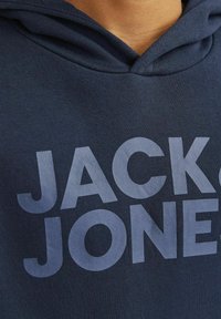 Kraljevo modra bombažna kapuca z velikim svetlomodrim logotipom "JACK & JONES". Ima kapuco s vrvico in mehak občutek.