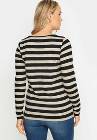 Raidallinen pitkähihainen paita, jossa on mustia ja béžin vaakaraidoituksia, pehmeää kangasta, pyöreä pääntie ja istuva malli.