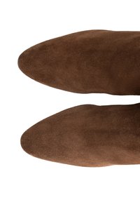 Brązowe zamszowe botki za kostkę z wydłużonym noskiem. Gładka tekstura o jednolitej formie, z zaokrąglonymi krawędziami i bez widocznych detali sprzętowych.