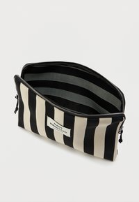 Czarna i beżowa torebka w paski z zamkiem błyskawicznym i wewnętrzną podszewką w paski. Posiada etykietę z nazwą marki z przodu.
