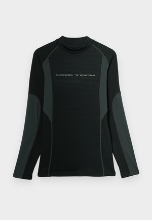 Camisa preta de manga longa com colarinho alto, feita de tecido texturizado. Apresenta painéis laterais cinzas e o logótipo "NIKE TECH" no peito.