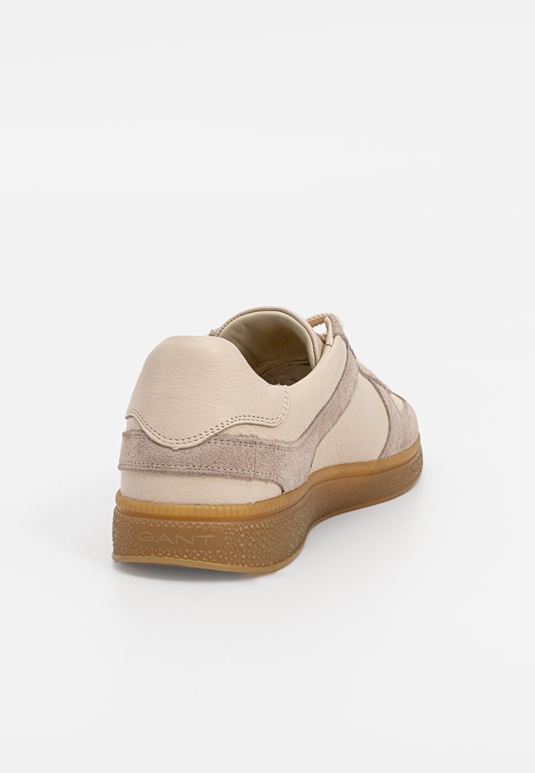 Beige Leder-Sneaker mit Wildlederakzenten, runder Form, strukturiertem Gummisohle und Branding an der Seite. Lässiges Design mit minimaler Detailgestaltung.