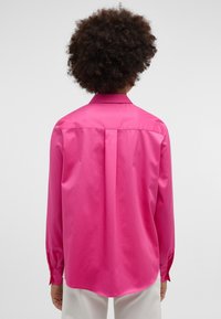 Long-sleeve shirt in bright pink, made from smooth fabric. Features a classic collar, pleat detail on the back, and buttoned cuffs.