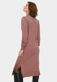 Pletene obleka v mauve barvi, z dolgimi rokavi, stranskimi razporki in oprijetim silhueto. Mehka tekstura z rebrastimi detajli na manšetah in robu.
