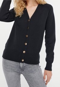 Černý v-neck kardigan vyrobený z jemné tkaniny, se zapínáním na knoflíky ve zlatém odstínu a úzkými dlouhými rukávy.