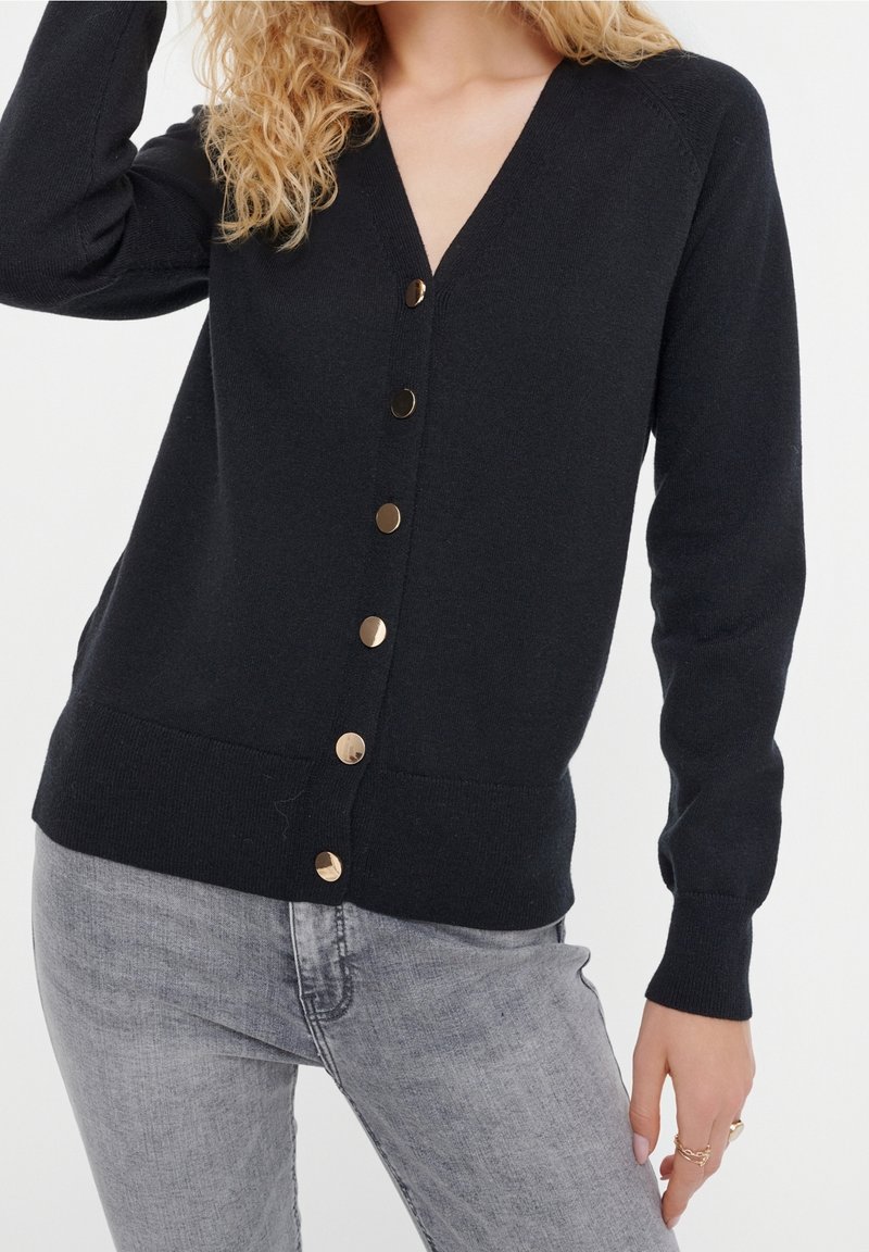 Černý v-neck kardigan vyrobený z jemné tkaniny, se zapínáním na knoflíky ve zlatém odstínu a úzkými dlouhými rukávy.