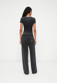 Zwarte getailleerde T-shirt met korte mouwen, gecombineerd met losse zwarte sweatpants met een elastische tailleband en een achterzak met geborduurde details.