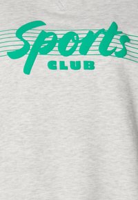 Szürke kapucnis pulóver, nagyméretű zöld "Sports" felirattal és annál kisebb "CLUB" felirattal, háttérben vízszintes csíkokkal.