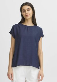 Top blu navy a maniche corte realizzato in tessuto testurizzato, con scollo rotondo e una vestibilità rilassata con orlo laterale spacco.