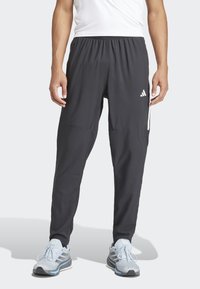 Schwarze Sporthosen mit elastischem Bund, taillierter Passform und weißen Akzentstreifen. Hergestellt aus leichtem Material. Mit Adidas-Logo.