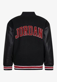 Veste varsity noire avec corps en laine, manches en cuir, et poignets rayés rouges et blancs côtelés. "JORDAN" brodé dans le dos.