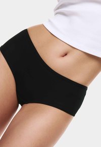 Černé bavlněné dívčí šortky s hladkou texturou, nízkým pasem a širokým pasem, kombinované s bílým přiléhavým topem.