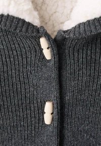 Czarny szary sweter z dzianiny o prążkowanej fakturze, z dwoma drewnianymi guzikami zapinającymi z przodu oraz miękką białą podszewką.