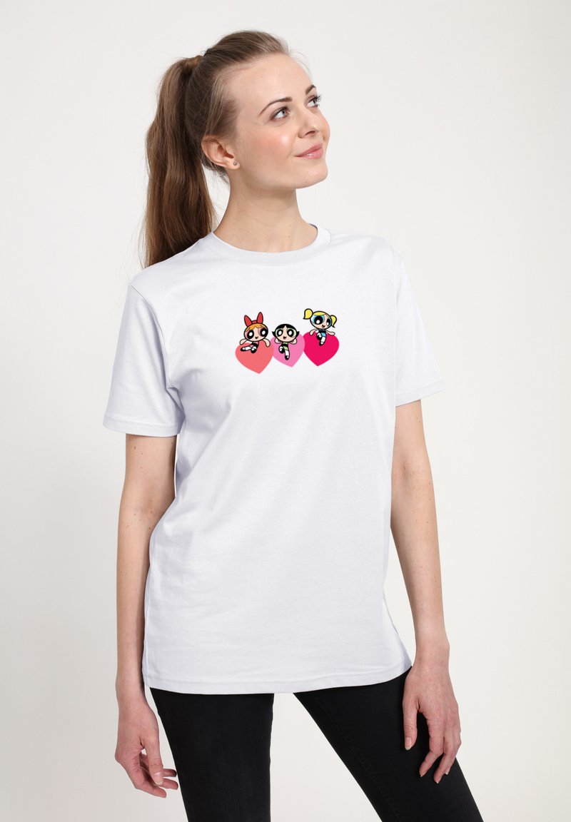 Camiseta blanca de manga corta con un gráfico de tres personajes de dibujos animados encima de formas de corazones rosas. Tejido suave, ajuste casual.