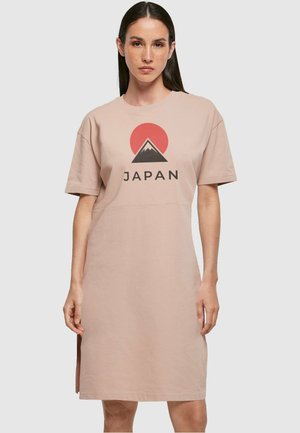 Jasnoróżowa bawełniana sukienka t-shirtowa z krótkimi rękawami, z grafiką przedstawiającą górę oraz napisem "JAPAN" w kolorze czarnym. Szczegół z bocznym rozcięciem.
