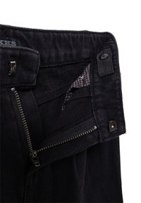 Pantaloni in denim nero con zip e chiusura a bottone; presenta una superficie liscia e una tasca interna foderata con un motivo a rete.