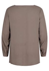 Blouse taupe à manches longues vue de dos, avec poignets boutonnés et coupe droite, ample. Aucun motif ni décoration visible.