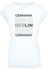 White t-shirt featuring black text. The words "GERMANY" and "BERLIN" are prominently displayed in various sizes and shades of gray.