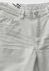 Pantaloni in denim grigio chiaro con chiusura a bottone, tasca frontale e una sottile texture con linee inclinate. Vestibilità standard con passanti per cintura.