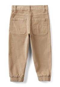 Béžové kordové kalhoty s elastickými manžetami, dvěma velkými zadními kapsami a poutky na opasek, zobrazené zezadu na bílém pozadí.