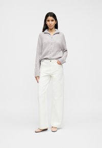 Ανοιχτό γκρι πουλόβερ με πλέξη καλώδιο και φερμουάρ στο λαιμό, συνδυασμένο με λευκό παντελόνι φαρδιάς γραμμής και μπεζ φλατ παπούτσια. Λείο ύφασμα, άνετη εφαρμογή.