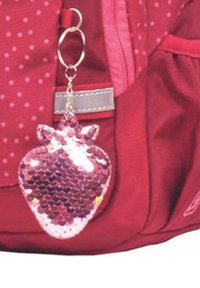 Roter Rucksack mit einem Schlüsselanhänger in Form einer Erdbeere aus Pailletten. Der Schlüsselanhänger hat glänzende pinke Pailletten, eine Herzform und kleine Ohren oben.