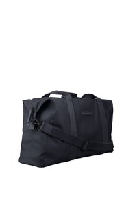 Sac de sport noir en tissu résistant. Comprend des poignées doubles, une bandoulière ajustable et un compartiment principal zippé.
