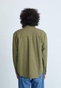 Groen geruit overhemd met een button-down kraag en lange mouwen, gemaakt van lichte stof. Recht model met een afgeronde onderrand.