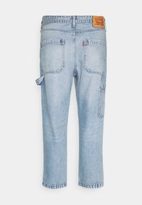 Ljust blå denim snickarbyxor med bakfickor, hammarslinga på sidan och en brun Levi's märkeslapp på midjan.